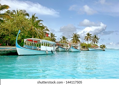 4 boats in a tropical resort island in Maldives. on one boat the maldivian flag is visible.