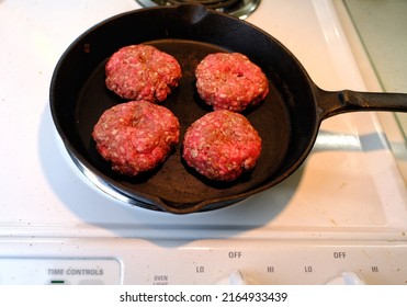 4 Burgers In Frying Pan On Stovetop