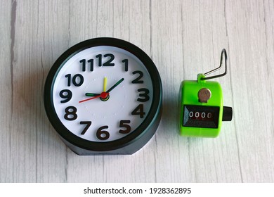 4 digits green tally counter or hand counter with alarm clock on the wooden background - Shutterstock ID 1928362895