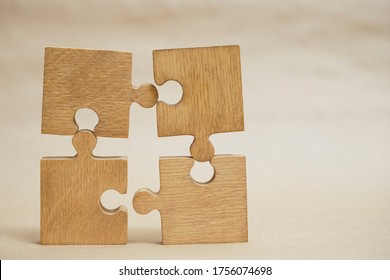 4 Four brown pieces of puzzle stand on wooden table isolated on yellow craft paper background. empty copy space for inscription or objects. idea, sign, symbol, concept of connecting