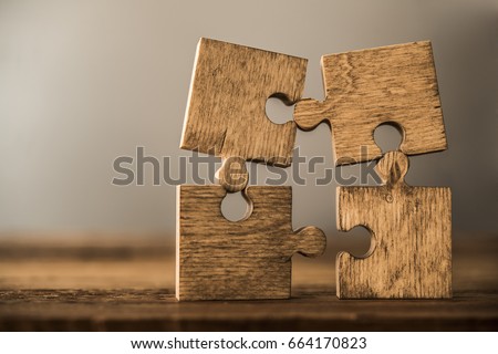 4 Four brown pieces of puzzle stand on wooden table isolated on gray or white background. empty copy space for inscription or objects. idea, sign, symbol, concept of connecting