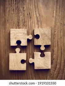 4 four wooden puzzle pieces. concept of connection people and brainstorming. isolated on wood background