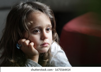 A 4 and half year old girl looks aside with a sad expression