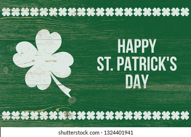 4 leaf clover and white text happy st. patrick's day over green wooden wall