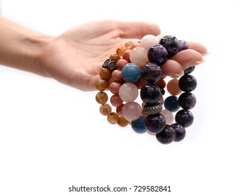 4 lucky stone bracelets in women hand on white background