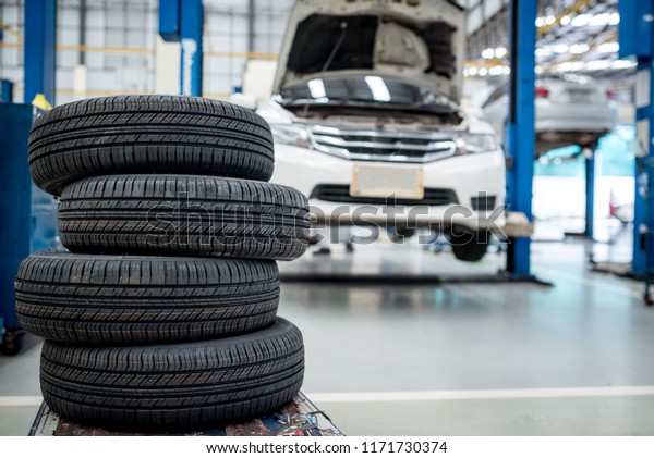 4 new tires that change tires in the auto\
repair service center, blurred background, the background is a new\
car in the stock blur for the industry, a four-wheeled tire set at\
a large warehouse