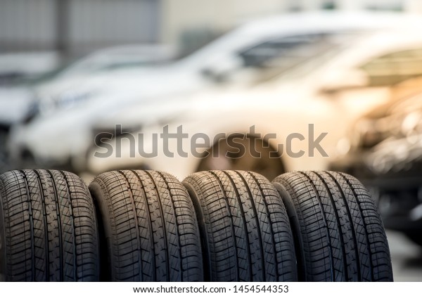4 new tires that change tires in the auto\
repair service center, blurred background, the background is a new\
car in the stock blur for the industry, a four-wheeled tire set at\
a large warehouse