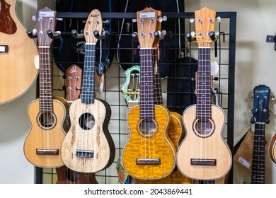 4 Small Traditional Havaiian Small Acoustic Guitars Ukulele Hanging On A Music Store.  LVIV, UKRAINE - AUGUST, 2021