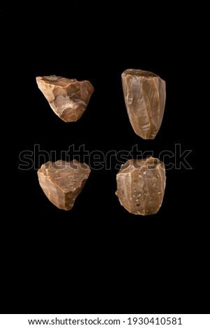 4 stones from the stone age. Remains of a nucleus from the Paleolithic era. on black background. An example of a prehistoric tool in perfect condition on a black background. The evolution of the human