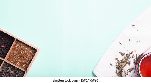 4 types of leaf tea of ​​green, black, herbal with flowers and hearts in a tea box and a mug of black tea on a light background with copy space, top view
