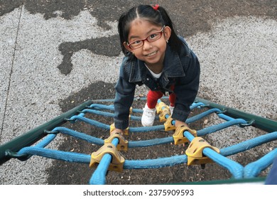 4 year old Latina brunette girl with eye glasses plays in the playground as therapy for Attention Deficit Hyperactivity Disorder ADHD - Powered by Shutterstock