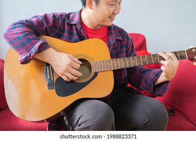 A 40 Year Old Asian Man Is Practicing Guitar. Person Playing Acoustic Guitar