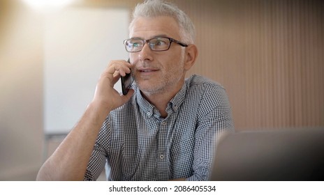 40 Year Old Man With Glasses On The Phone In An Office