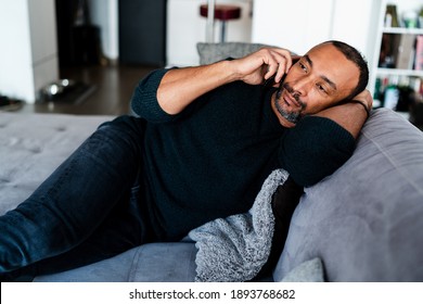 40 Years Old Man Relaxing On The Sofa At Home And Talking On The Phone