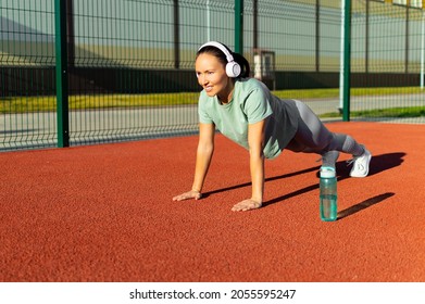 40 Years Old Woman Doing Push-ups On The Sports Ground. Workout And Healthy Lifestyle Concept.