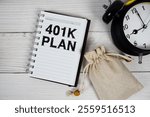 401K Plan text on notepad with money bag and alarm clock on wooden background