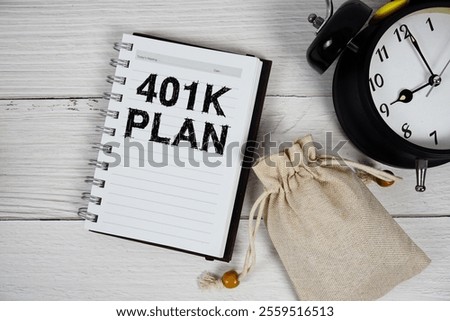 401K Plan text on notepad with money bag and alarm clock on wooden background