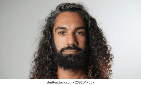 40s man with long curly hair look camera. Sad young adult guy portrait. One 30 year old cute person. Nice wavy beard close up. Male arab face head shot. Serious mixed hindu model. Nose piercing style - Powered by Shutterstock