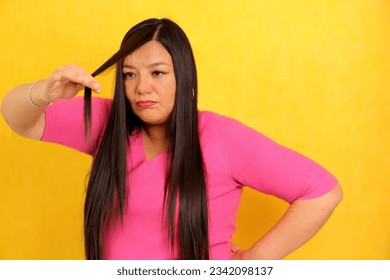 40-year-old Latina woman suffers when she sees the ends of her hair split and damaged by lack of care - Shutterstock ID 2342098137