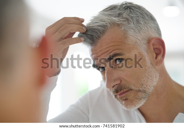 40-year-old man\
checking hair in front of\
mirror