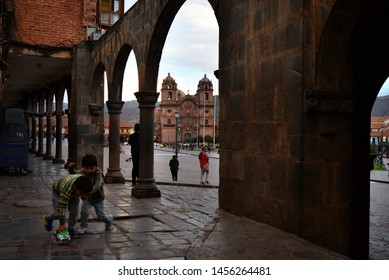 4-25-2018 Cusco, Peru. View On The Cathedral And The Main Square, Kids Playing Under The Arches.