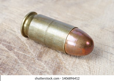 .45 ACP (Automatic Colt Pistol), or .45 Auto (11.43x23mm) a handgun cartridge designed by John Browning in 1905 on wooden background