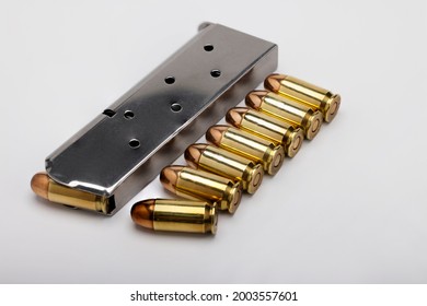 .45 ACP bullets and gun magazine on white background