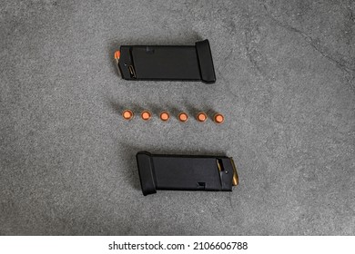 45 ACP caliber hollow point and full metal jacket bullets loaded into handgun magazines and unfired rounds lined up on a stone surface