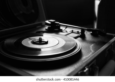 45 record vinyl disc on a vintage portable turntable. Black and white picture