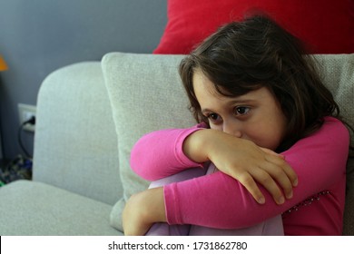 4-5 Year Old Girl Looks At The TV Sitting On The Sofa At Home