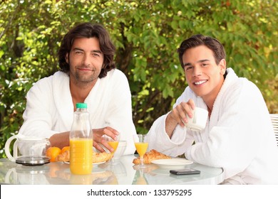 45 Years Old Man And A 20 Years Old Man Dressed In Bathrobe Drinking Coffee At Breakfast