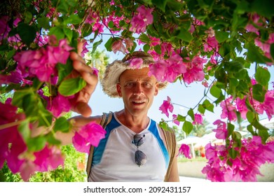 45-50 Year Old Man Of Athletic Build With A Backpack In Hurgada Egypt Covered With Pink Flowers.Concept: Hiking And Trekking.