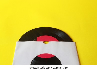 45rpm Vinyl Record With Sleeve. Close Up Vinyl On Yellow Background. 