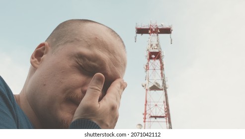 4G And 5G Cellular Radio Tower, The Man Has A Bad Headache. The Concept Of Harmful Effects Of Powerful Radio Waves, High Frequency On Human Health