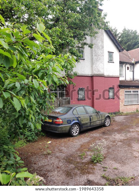 4June21, Watford, London,\
uk. an old dark blue BMW looks abandoned and neglected infront of a\
house