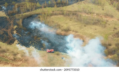 4K Aerial View Spring Dry Grass Burns During Drought Hot Weather. Bush Fire And Smoke. Fire Engine, Fire Truck On Firefighting Operation. Wild Open Fire Destroys Grass. Ecological Problem Air