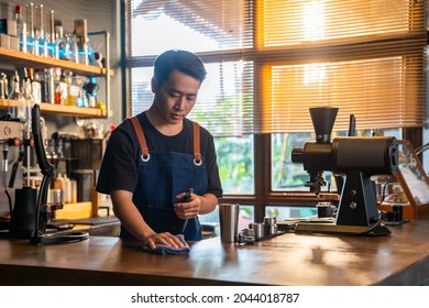 4K Asian Man Barista Using Towel Sweeping Counter Bar With Alcohol Sanitizer Before Opening Cafe. Male Waiter Cleaning Up Coffee Shop For Service To Customer. Small Business Owner Working Concept