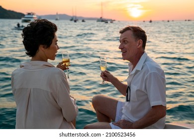 4K Caucasian Couple Enjoy Outdoor Luxury Party Drinking Champagne With Talking Together While Catamaran Boat Sailing At Sunset. Man And Woman Relax With Outdoor Lifestyle On Summer Travel Vacation