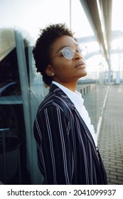 4k. Travel, Digital. Charming African American woman in elegant striped suit. Stands by the glass wall and waiting for her flight. Businesswoman or student. Thoughts. Sky.