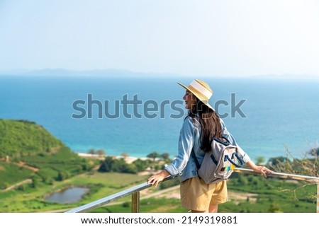 4K Young beautiful Asian woman with backpack solo travel on tropical island mountain peak in summer sunny day. Cheerful female relax and enjoy outdoor lifestyle in summer beach holiday vacation trip