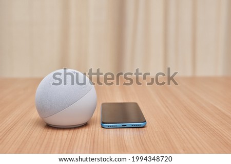 4th generation echo dot with a smartphone next to it