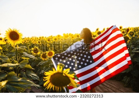 4th of July. Amazing woman with the American flag in a sunflower field. Freedom day.  Independence Day. Patriotic concept