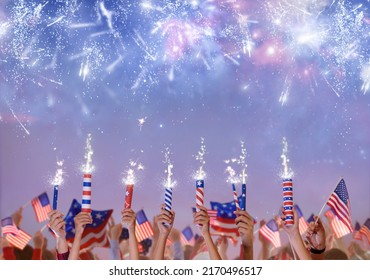 4th of July in America. USA Independence day fireworks. Hands holding firecrackers, sparkler and American flag celebrating US patriotic holiday. Patriots cheering for freedom.