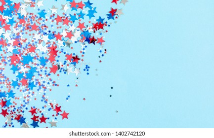 4th of July American Independence Day. Red, blue and white star confetti decorations on blue background. Flat lay, top view, copy space