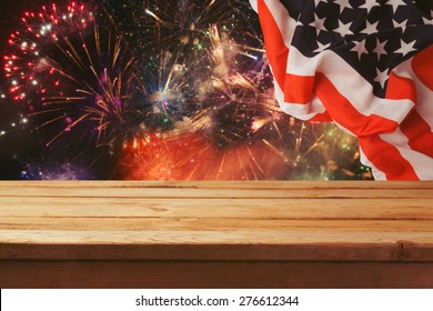 4th Of July Background. Wooden Table Over Fireworks And USA Flag. Independence Day Celebration