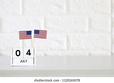 4th Of July Calendar And American Flag On The Table White Brick Wall Background Concept Happy Independence Day