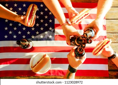 4th of July celebration party, young men hands holding beer bottle, holiday label design, Happy Independence day, hot dog, mustard, catchup. American flag, river recreation area. Close up, background - Powered by Shutterstock