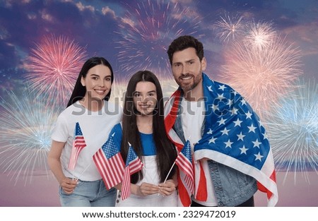 4th of July - Independence day of America. Happy family with national flags of United States against sky with fireworks