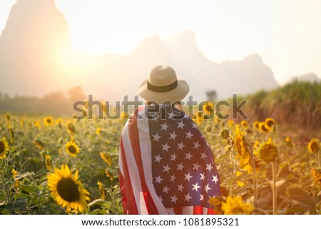 4th July memorial day concept by woman is cover by USA flag in the sunflower field.