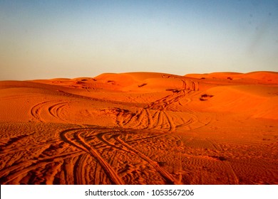 4WD tyre tracks weave through the red sand dunes of the Wahiba Sands desert in Oman on the Arabian Peninsula